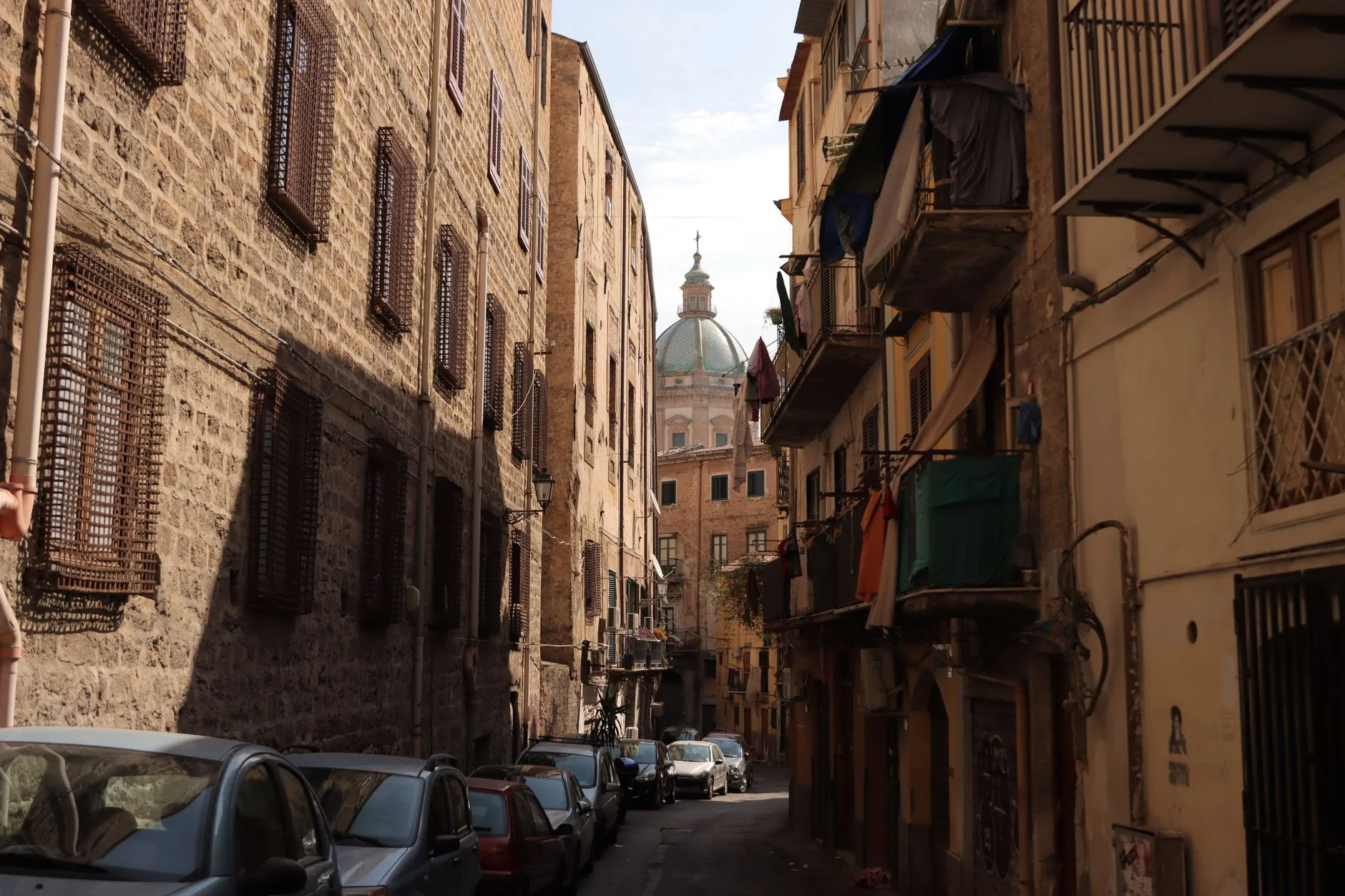 Rue pavée du centre historique de Palerme avec panneau ZTL et voitures garées